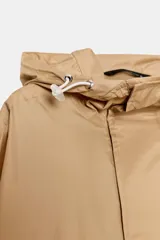 Cazadora tipo anorak de cuello subido con capucha ajustable mediante cordones elásticos y stoppers. Presenta manga larga, un bolsillo frontal de plastrón con solapa, y cintura y bajo ajustables con cordones elásticos. Cierre frontal con botones a presión.