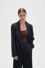 Blazer de corte holgado con diseño de rayas verticales, cuello solapa y cierre frontal con un botón. Cuenta con bolsillos laterales con solapa.