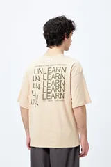 Remera blanca de corte amplio con mangas cortas y estampado con la frase "Unlearn" en el frente y gráfico en la espalda.
