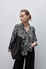 Camisa de calce amplio confeccionada en viscosa fluida con estampado animal print tipo cebra en blanco y negro. Presenta cuello camisero, escote en V y mangas largas con puños elastizados, además de frunces en el canesú que aportan volumen.