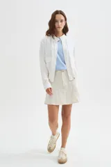 Chaqueta bomber blanca de algodón con cuello mao, bordado sutil, bolsillos frontales con solapa, cierre de botones y cordón ajustable en el ruedo.