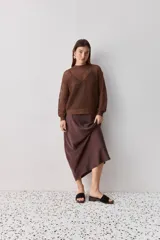 Falda midi color negro al bies, confeccionada en tela de textura suave y caída fluida, de diseño minimalista y silueta recta.