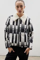 Campera con cierre frontal, cuello de sherpa en color crema y diseño estampado geométrico en blanco y negro. Cuenta con elástico ajustable en la cintura.