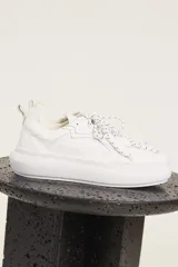 Zapatillas urbanas blancas de cuero con cordones moteados en blanco y negro y suela chunky.