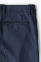 Pantalón de traje de corte ajustado, con cierre frontal y corchete oculto. Presenta bolsillos laterales, bolsillos traseros ribeteados y raya marcada en el frente.