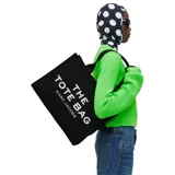 Bolso tote de gran tamaño Marc Jacobs, confeccionado en lona de algodón negra con el logo estampado en blanco en el frente. Cuenta con asas superiores reforzadas y una estructura amplia y resistente.