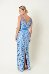 Vestido largo de fiesta celeste con encaje floral, hombros descubiertos con tul y lazo azul en la cintura.