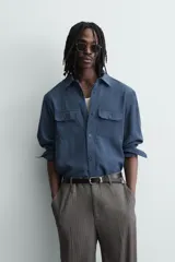 Camisa de corte relajado confeccionada en tejido con mezcla de viscosa. Presenta cuello solapa, manga larga con puños abotonados, bolsillos de plastrón con solapa en el pecho y cierre frontal de botones.