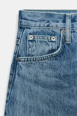 Jeans de tiro alto con corte tapered y largo al tobillo. Presenta cinco bolsillos, trabillas en la cintura, cierre frontal con cremallera y botón, y detalle de raya planchada en el delantero.