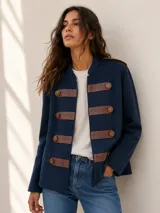 Campera estilo militar color azul marino, con cuello redondo y detalles de tiras en cuero marrón con botones metálicos dorados en el frente.