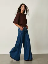 Jean de denim azul de tiro medio, con diseño wide leg de corte muy amplio y pinzas laterales decorativas que aportan volumen.