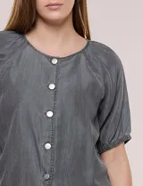 Blusa de calce relajado de lyocell en tono azul denim, con cuello a la base y cierre frontal de botones metálicos. Tiene mangas cortas abullonadas con puños elásticos.