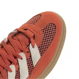 Zapatilla Adidas Handball Spezial, color naranja quemado con tres franjas laterales en color crema. Presenta paneles laterales de malla y puntera de gamuza. La suela es de goma color gum (marrón claro).