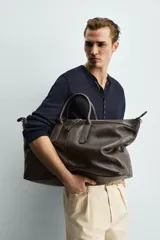 Bolso shopper de hombro fabricado en piel con acabado abatanado. Cuenta con compartimento principal con cierre de cremallera, interior con bolsillo plano y bolsillo con cierre. Incluye dos asas de mano, asa de hombro y detalle de llavero colgante.