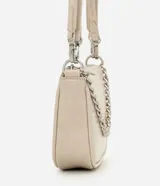 Cartera de mano tipo baguette, de color beige, con cierre superior de cremallera y una cadena decorativa plateada en la parte frontal. Cuenta con una correa larga ajustable y extraíble para usar al hombro o cruzada.