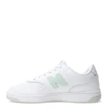 Championes New Balance de estilo urbano, confeccionados en cuero y materiales sintéticos. Presentan un diseño de silueta limpia en color blanco con detalles en verde menta en el logo lateral, la lengüeta y la suela. Cuentan con cierre de cordones y plantilla de EVA para mayor amortiguación.