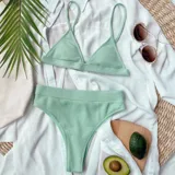 Bikini de dos piezas color verde agua, confeccionado en tela acanalada. La parte superior es de estilo triángulo con breteles finos, y la parte inferior es de tiro alto con corte clásico.