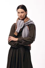 Polera de tejido de punto color marrón, con cuello alto y diseño de trenzas verticales. Presenta mangas largas con puños ajustados y un detalle de panel lateral asimétrico que se anuda en la cintura.