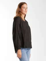 Blusa de algodón color negro con bordados florales al tono. Presenta escote en V con terminación festoneada y mangas largas con puños fruncidos.