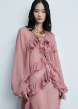 Vestido largo de gasa semitransparente en color rosado, con diseño de volantes verticales en el frente, escote en pico con cierre de lazo y mangas largas abullonadas. Incluye forro interior.