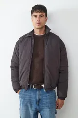 Campera acolchada de color gris oscuro, con diseño de cuello tipo camisa, cierre frontal con cremallera y bolsillos laterales. Presenta puños y ruedo con elástico.