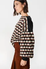 Sweater de punto con diseño geométrico de ondas en colores negro, marrón y crema. Presenta cuello redondo, mangas largas abullonadas con puños acanalados en color negro y un corte holgado.