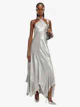 Maxivestido plateado de tejido laminado ligero, con escote halter fruncido, detalle metálico Oval D y espalda abierta con lazos.