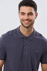 Remera polo de manga corta en color azul marino, con estampado sutil de pequeños motivos geométricos, cuello camisero y cartera con tres botones.
