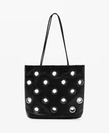 Bolso tipo shopper de color negro con diseño de ojales metálicos plateados. Cuenta con doble asa de hombro y cierre de botón magnético.