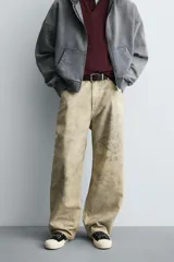 Pantalón de corte baggy fit confeccionado en tejido de algodón con textura y efecto lavado. Presenta diseño de cinco bolsillos, cierre frontal con cremallera y botón.