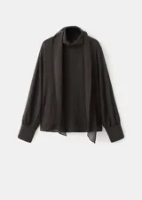 Blusa de color marrón oscuro con textura, cuello alto envolvente con detalle de fular integrado, manga larga con puños abotonados y diseño recto.