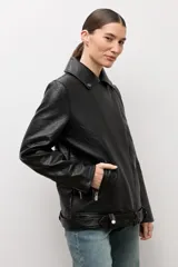 Chaqueta biker de eco cuero color negro, con solapas amplias, cierre cruzado asimétrico, bolsillos laterales con cierre y cinturón ajustable en el dobladillo.