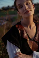 Chaleco tejido negro con cuello en V y aplique de cuero marrón.