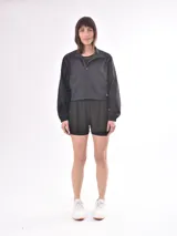 Campera corta deportiva color negro, con cuello alto, cierre frontal y mangas largas.