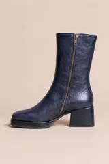 Botas de caña media en cuero azul oscuro con textura arrugada, diseño de punta cuadrada, taco cuadrado y cierre lateral.