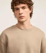 Sweater color beige de algodón y poliéster, de corte holgado, cuello redondo y mangas largas.