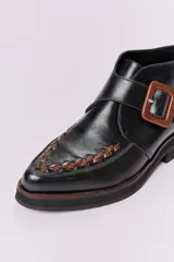 Botín de cuero negro con detalle de trama marrón en la puntera y hebilla cuadrada color carey.