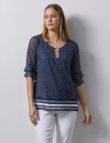 Blusa Harper de microtul estampado azul con lunares blancos, cuello redondo, escote en U con aplique de aros y mangas cortas amplias.