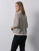 Blusa de gasa estampada con líneas verticales negras sobre fondo beige, de manga larga con puño abotonado. Espalda con abertura y botón.