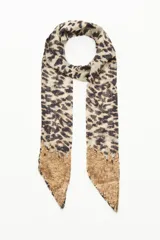 Corbatín largo de tela liviana con estampado animal print y detalle de lentejuelas doradas en los extremos.