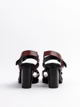 Sandalias negras de cuero vacuno con tiras, detalles de gemelos en bronce, taco de madera y plataforma de EVA.