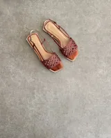 Sandalias chatas de cuero marrón con diseño trenzado en la capellada, punta cuadrada y tira ajustable al talón.