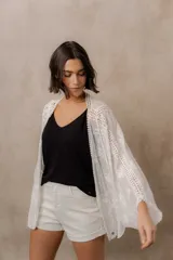 Kimono marfil de silueta amplia, confeccionado en tela con bordados florales y detalles calados. Cuenta con mangas amplias tres cuartos, frente abierto y terminaciones decorativas.