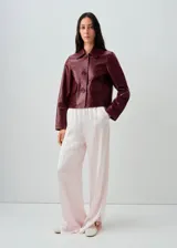 Chaqueta de cuero de corte recto con cuello camisero, cierre frontal de botones y dos bolsillos de parche con solapa en la parte delantera.