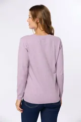 Buzo tejido en hilo de algodón color beige, con cuello redondo y manga larga. Presenta un corte clásico y un pequeño detalle metálico en la parte inferior izquierda.