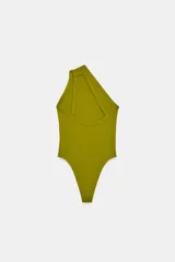 Body de tejido liso color azul claro, con escote asimétrico de un solo hombro y cierre inferior con broches a presión.