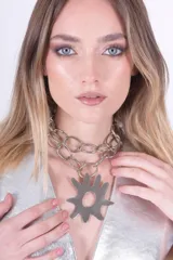 Collar plateado con cadena de eslabones grandes y dije en forma de sol con puntas redondeadas.