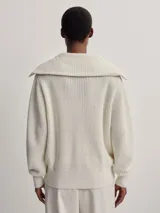 Campera larga tejida color crema con cierre frontal, cuello alto y diseño texturizado.