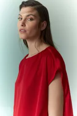 Blusa roja de satén con cuello redondo y mangas cortas.