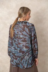 Blusa de gasa con estampado abstracto en tonos verdes y marrones, con detalles de hilos dorados. Presenta cuello camisero con escote en V, mangas largas con puños elásticos y un corte holgado.